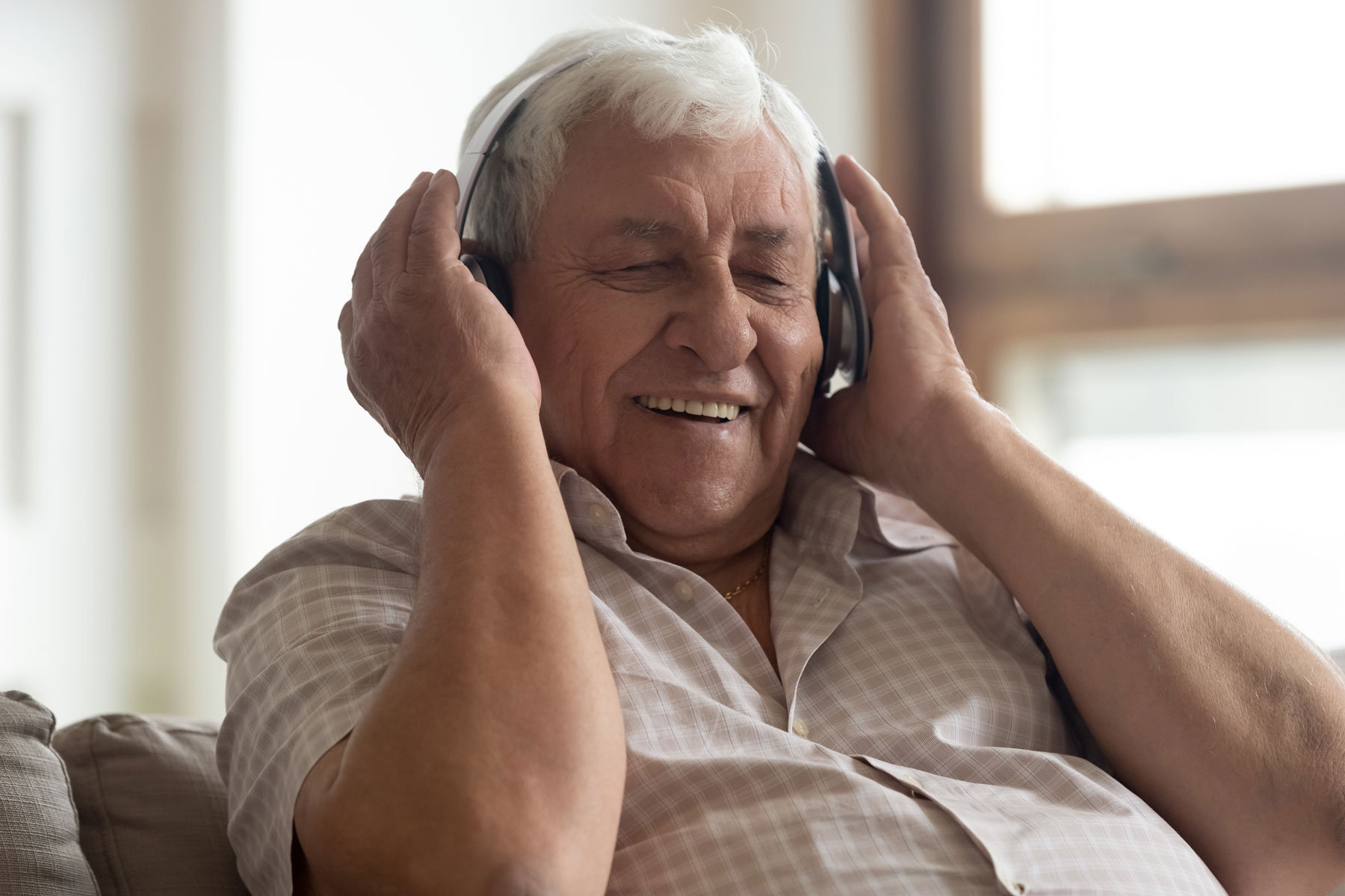 a senior man listens to music on headphones